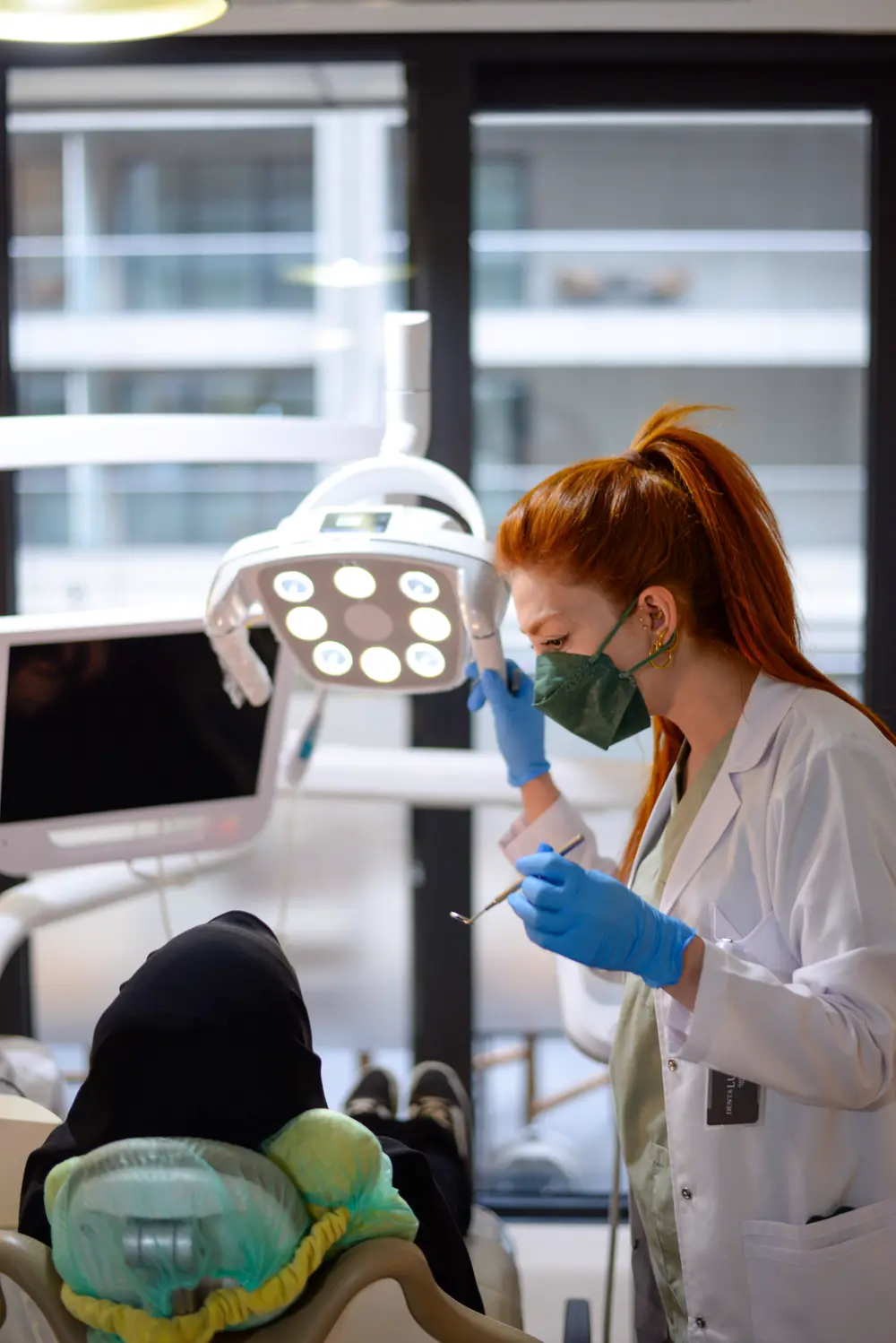 Dentist in mask and gloves working under a treatment lamp