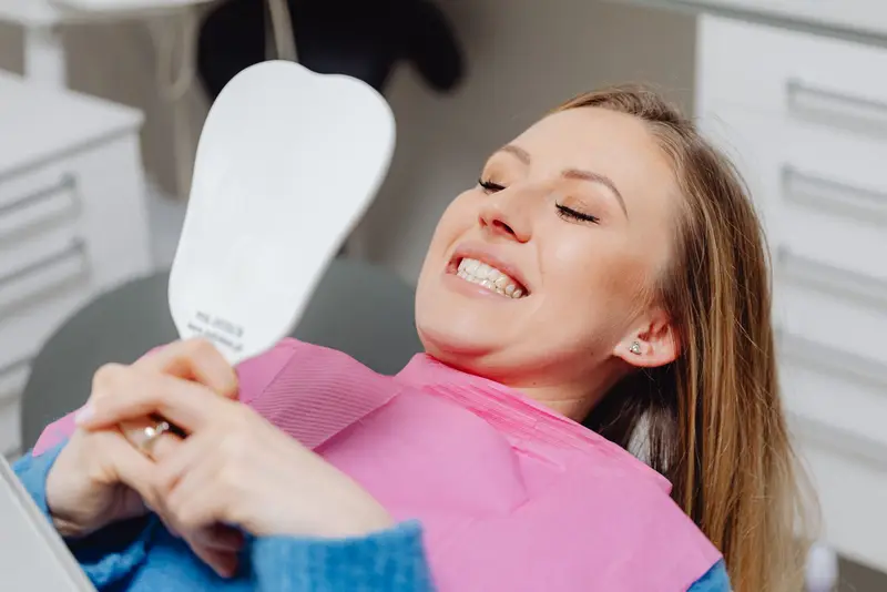 Smiling woman holding a hand mirror in a dental chair